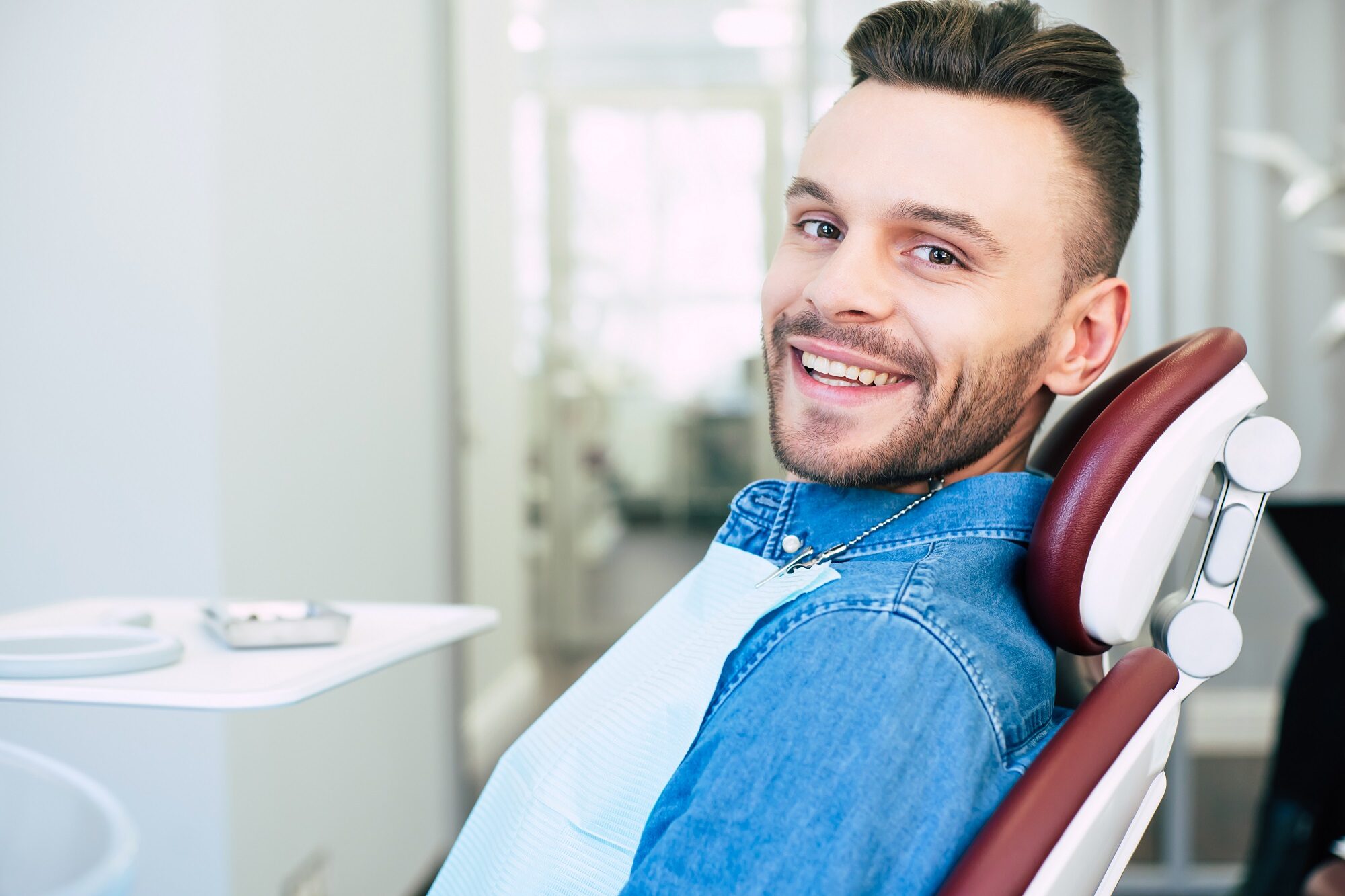 A smiling man sits in a dental chair, ready for his appointment - dental checkup A smiling man sits in a dental chair, ready for his appointment - dental checkup