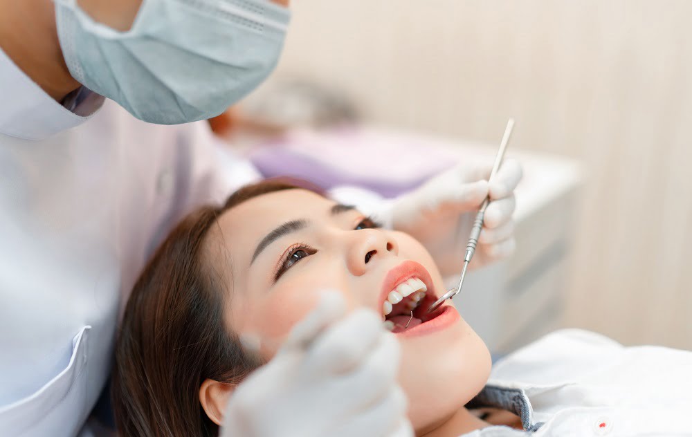 A dentist examines a patient's teeth with a dental mirror and scaler - dental checkup A dentist examines a patient's teeth with a dental mirror and scaler - dental checkup