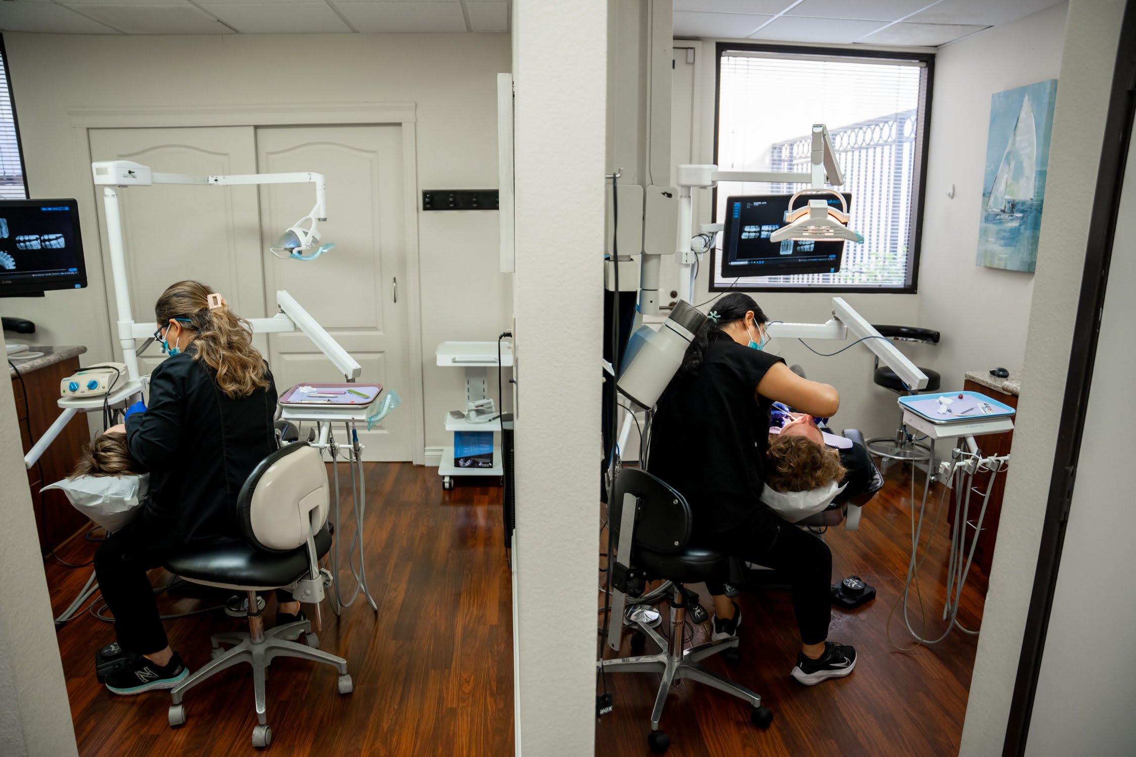 Two dental professionals are seen working on patients in separate treatment rooms, using modern dental equipment - professional teeth whitening Two dental professionals are seen working on patients in separate treatment rooms, using modern dental equipment - professional teeth whitening