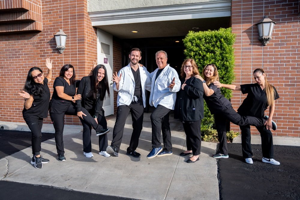 The dental care of team of Dental Wellness of Los Alamitos; Dr. Chris Gipe, Cindy Kasi, Ginger, Misty, Maria, Lyndsay, Karen posing in front of the dental clinic - dental implants The dental care of team of Dental Wellness of Los Alamitos; Dr. Chris Gipe, Cindy Kasi, Ginger, Misty, Maria, Lyndsay, Karen posing in front of the dental clinic - dental implants