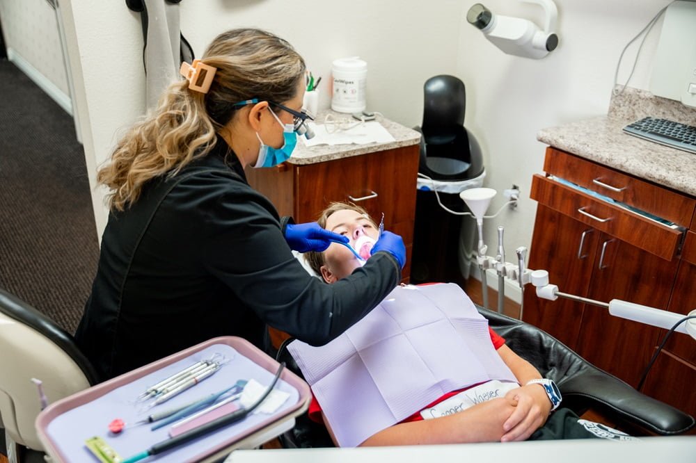 Registered Dental Hygienist Cindy Kasi examines a young patient's teeth in a dental office - dental emergency Registered Dental Hygienist Cindy Kasi examines a young patient's teeth in a dental office - dental emergency