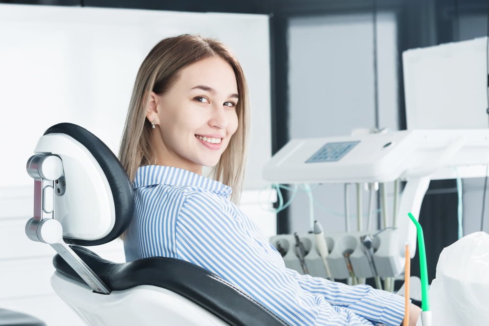 A young woman smiles while sitting in a dental chair, ready for her appointment - root canal A young woman smiles while sitting in a dental chair, ready for her appointment - root canal