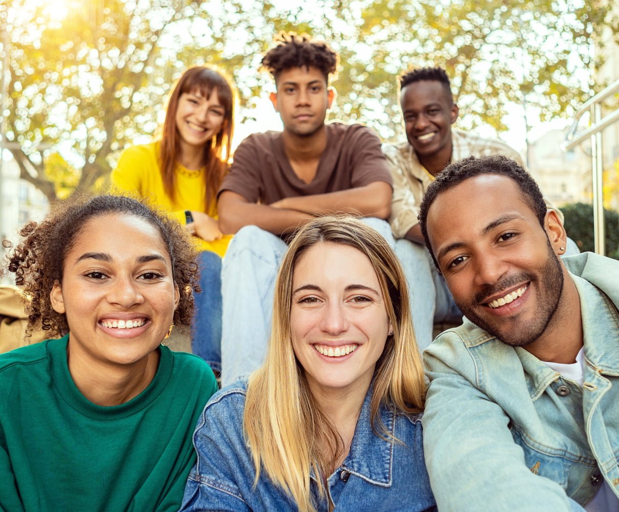 A group of six friends smiles at the camera while sitting outdoors on a sunny day, enjoying their time together - Dentist in Los Alamitos CA A group of six friends smiles at the camera while sitting outdoors on a sunny day, enjoying their time together - Dentist in Los Alamitos CA