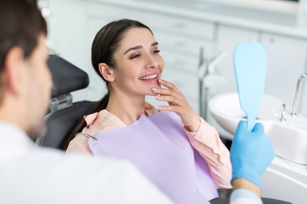 Assistant perform a procedure on a patient in a dental office, both wearing masks and protective eyewear - dental crowns and bridges