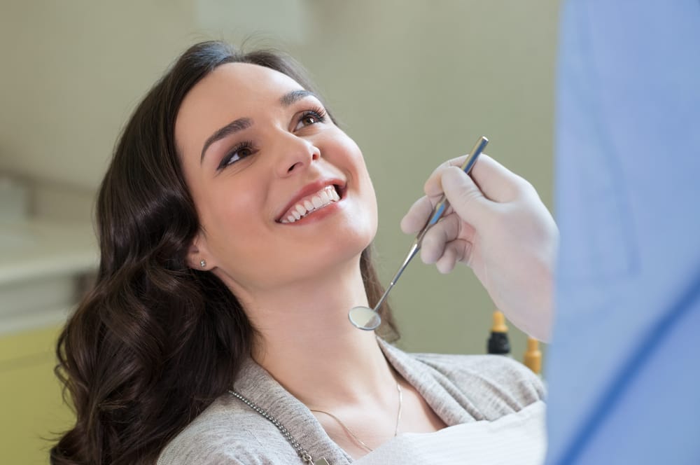 Smiling Patient Receiving Dental Checkup – Restorative Dentistry Long Beach A cheerful woman sits in a dental chair during an oral examination, demonstrating trust and satisfaction with quality restorative dental care – Restorative Dentistry Long Beach.